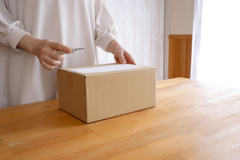 届いた段ボール箱を開ける手元(イメージ写真)