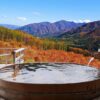 紅葉の山を望む温泉の露天風呂(秋の旅行イメージ)