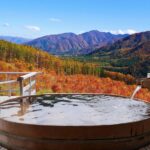 紅葉の山を望む温泉の露天風呂（秋の旅行イメージ）