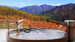 紅葉の山を望む温泉の露天風呂（秋の旅行イメージ）