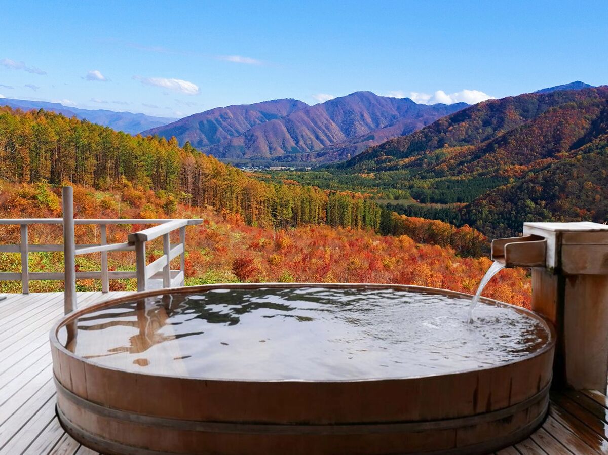 紅葉の山を望む温泉の露天風呂(秋の旅行イメージ)