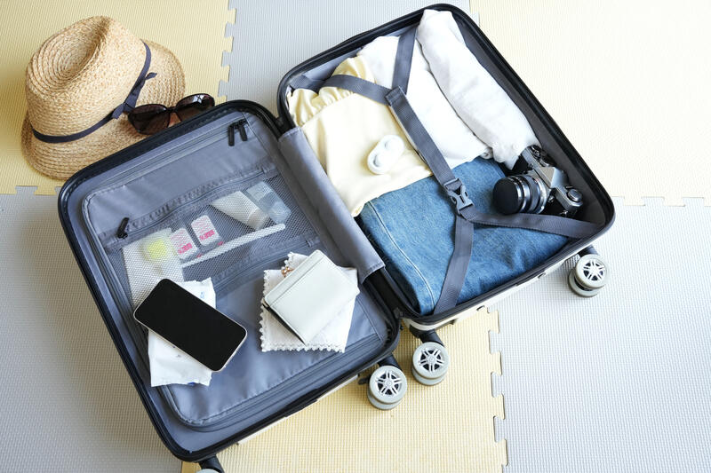 スーツケースに衣類やカメラを詰める旅行の荷造り